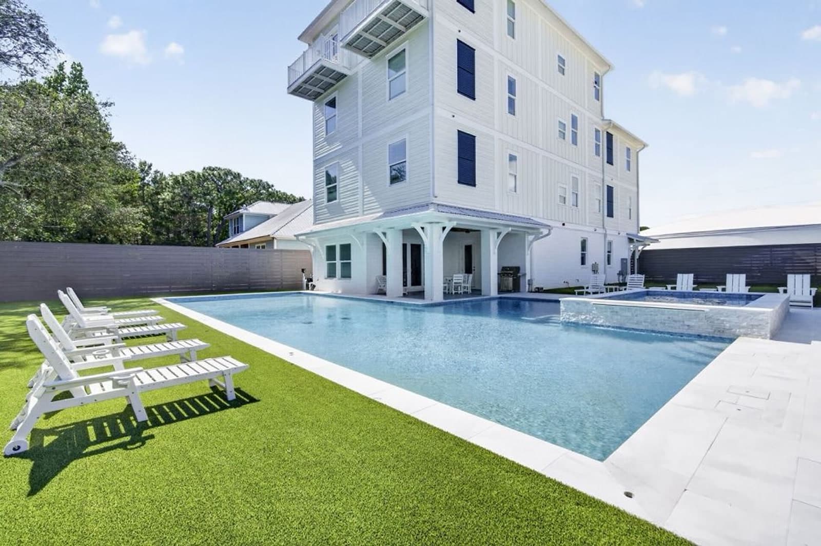 Large rectangular pool and raised spa beside a multi-storey coastal home